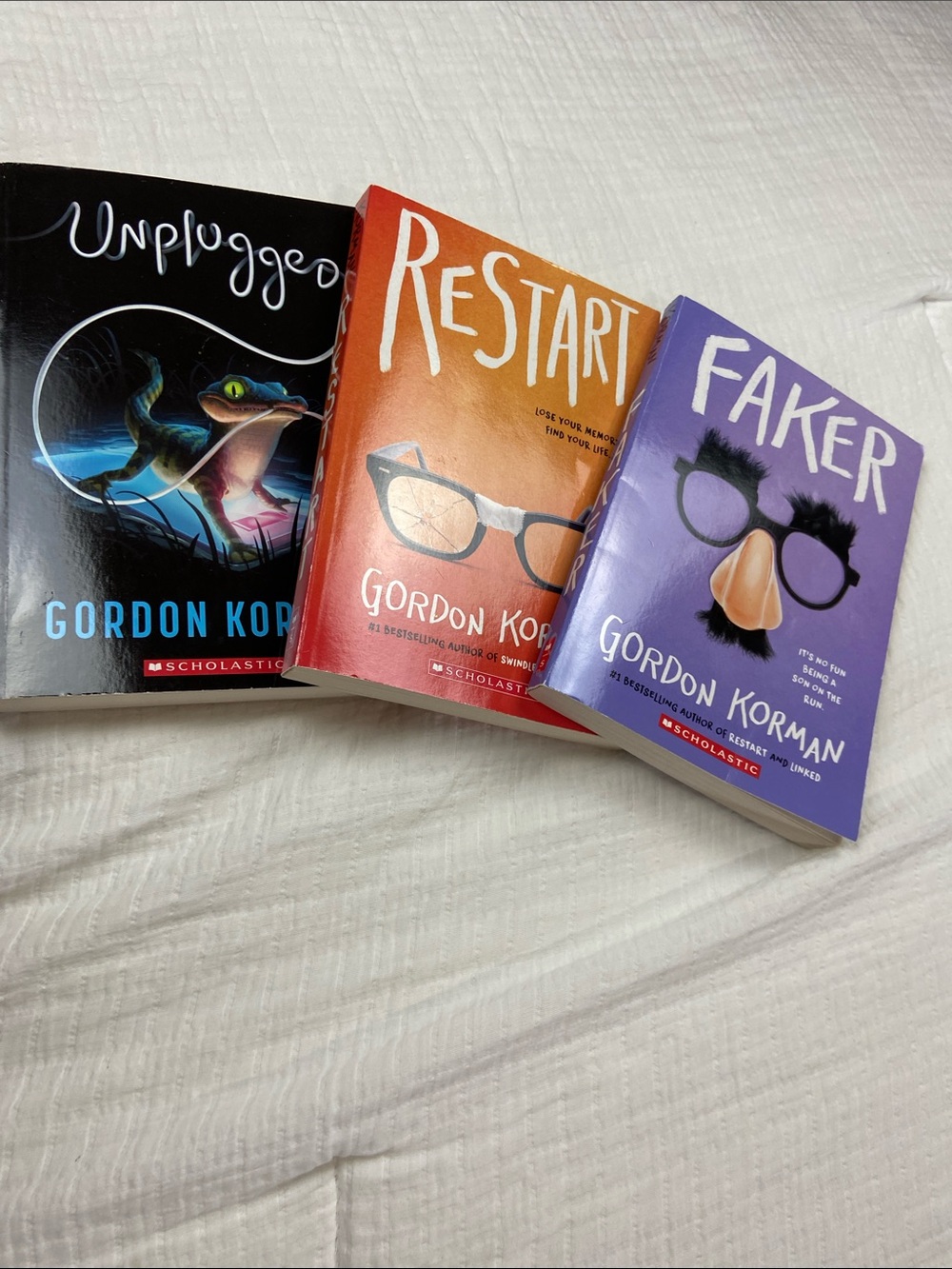 Three non series Gordon Korman books, Unplugged, Faker, and Restart.